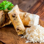 Meerrettich: Stücke von Meerrettichwurzel und geriebener Meerrettich auf einem Holzbrett.